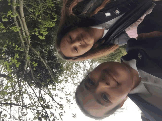two girls are standing next to each other with one wearing a jacket with the letter l on the front