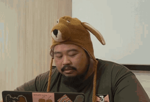 a man wearing a hat that says always love looks at his laptop