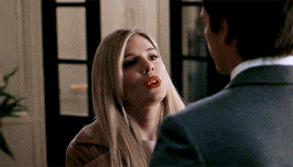 a man in a suit and a woman in a coat are looking at each other