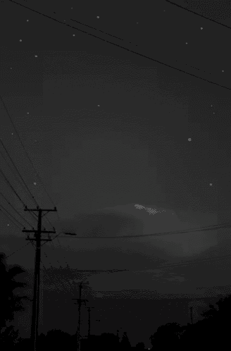 a black and white photo of a shooting star in a dark night sky