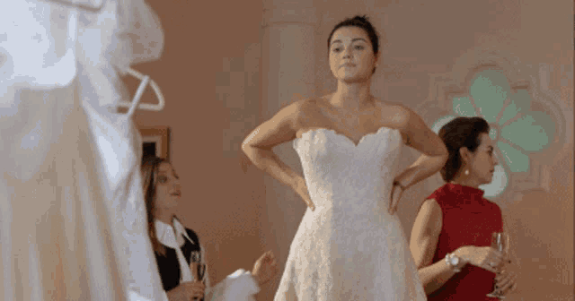 a woman is trying on a wedding dress while another woman looks on