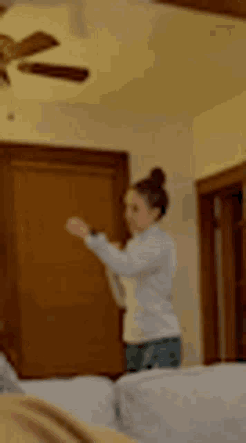 a woman is standing in a living room with a ceiling fan and a couch .
