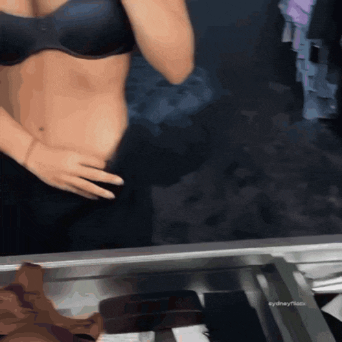 a woman in a black bra is standing in front of a mirror with the hashtag #sydneytissotx