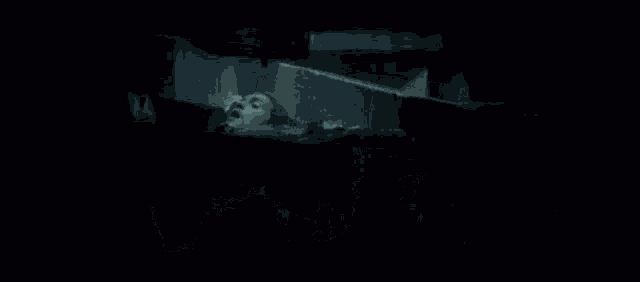 a group of people are standing in a dark room and looking out a window .