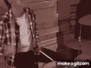 a man in a plaid shirt is playing the drums .