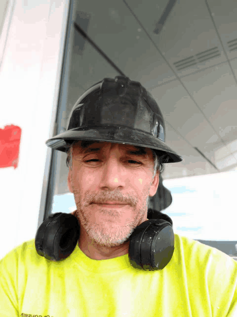 a man wearing a hard hat and headphones is wearing a neon yellow shirt that says ' air conditioning ' on it