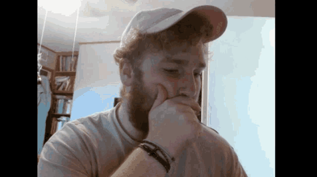 a man with a beard wearing a white hat with the letter t on it