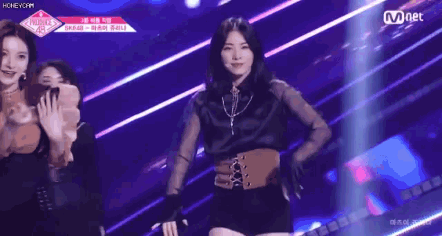 a woman is dancing on a stage in front of a crowd while wearing a black shirt and a brown belt .
