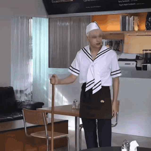 a man in a sailor outfit is holding a cane in front of a sign that says spicy sandwich