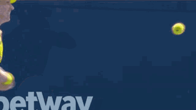 a woman in a yellow tank top is holding a tennis racket in front of a sign that says betway