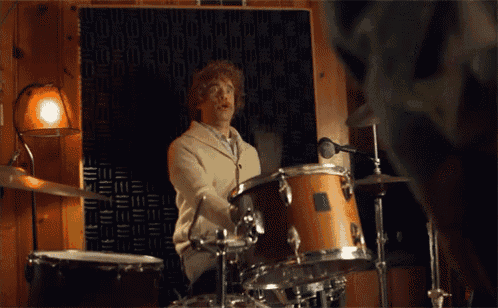 a man is playing drums in a room with a microphone