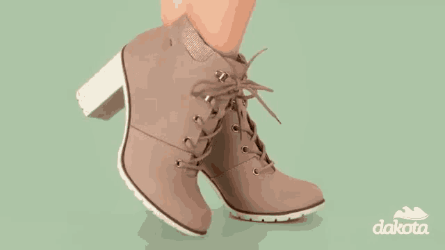 a woman is wearing a pair of tan lace up boots .