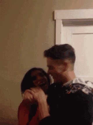 a man and a woman are hugging each other in a room