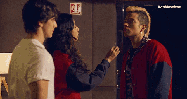 a man in a red jacket stands next to a woman in a red shirt and a man in a white shirt