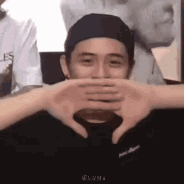 a man is making a heart with his hands .