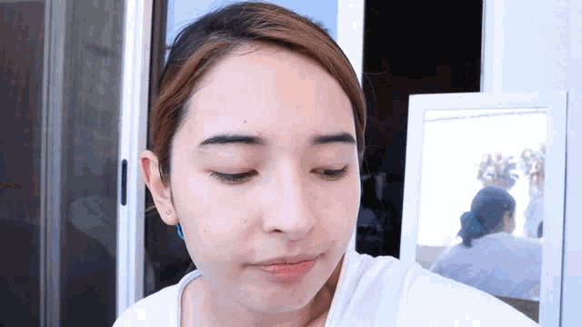 a woman looks at her face in a mirror