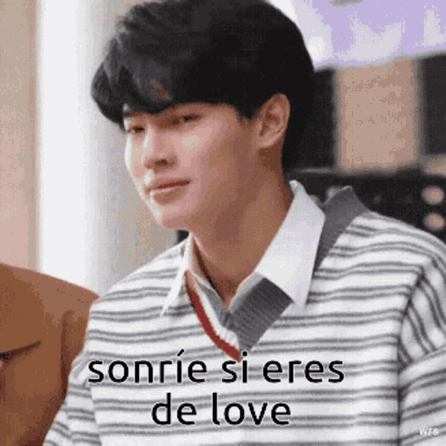 a young man wearing a striped sweater is smiling with the words sonrie si eres de love above him .