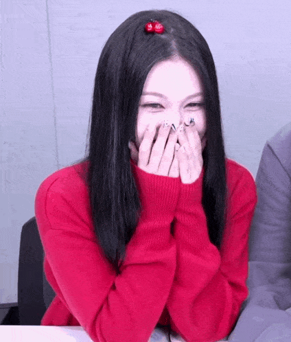 a woman in a red sweater is covering her face with her hands