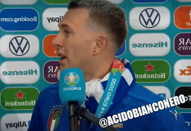 a man speaking into a microphone with a badge around his neck that says ' uefa ' on it