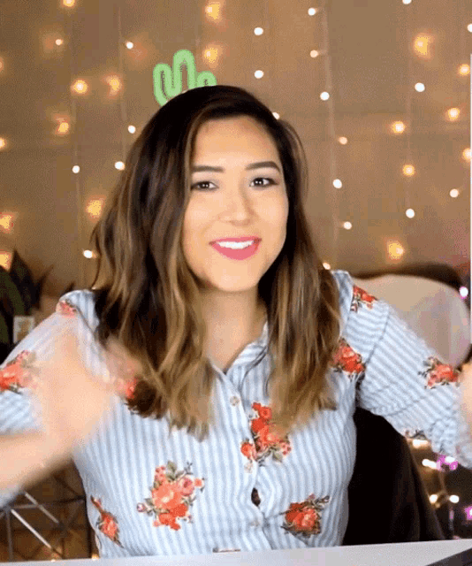 a woman wearing a striped shirt with flowers on it looks at the camera