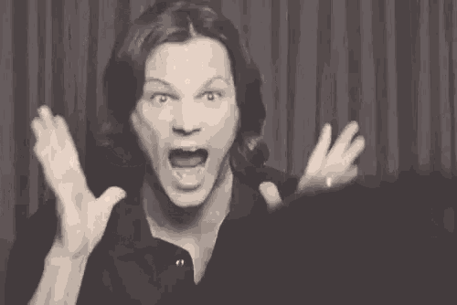 a black and white photo of a man making a funny face with his hands in the air .
