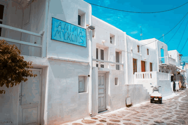 a white building with a blue sign that says " anna mykonos "