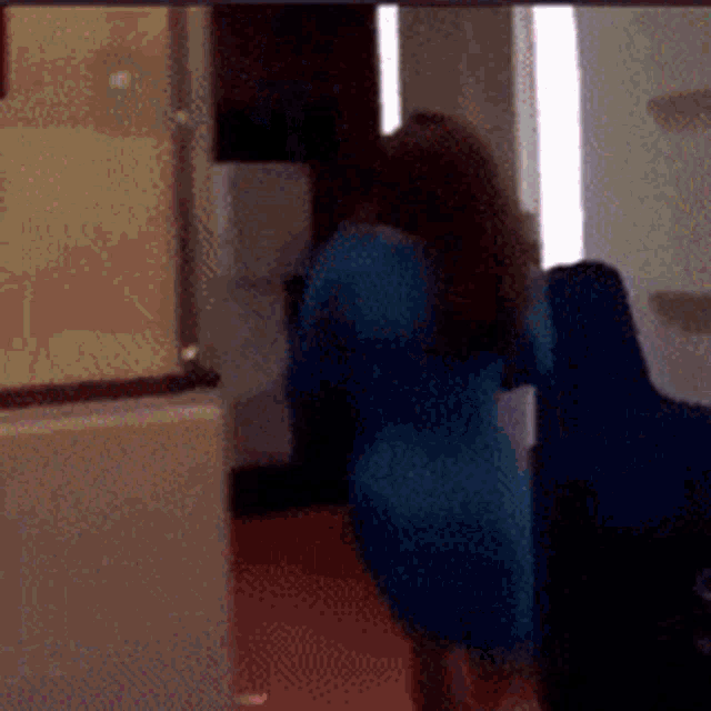 a woman in a blue dress is dancing in a room