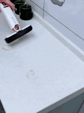 a person is using a vacuum cleaner to clean a counter .