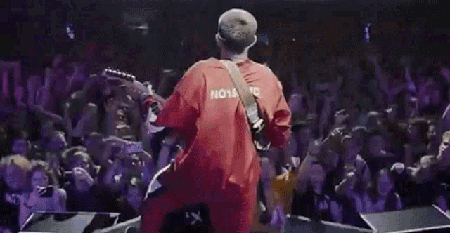a man is playing a guitar on a stage in front of a crowd .