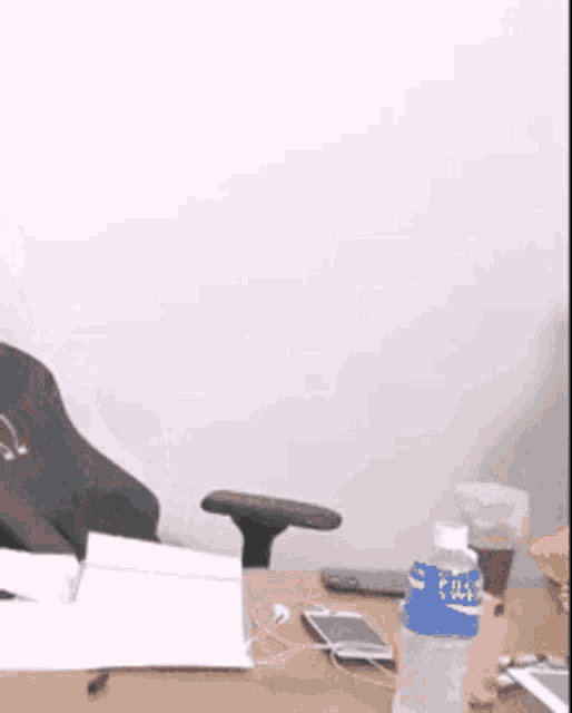 a man is sitting at a desk with a bottle of water .