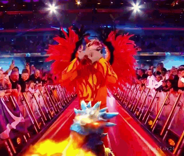 a man in a flaming costume is walking down a red carpet in front of a crowd ..