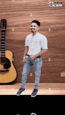 a man in a white shirt is standing in front of a guitar .
