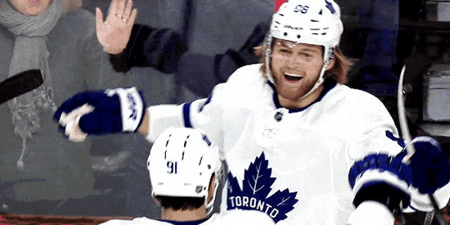 a hockey player wearing a white jersey with toronto on it