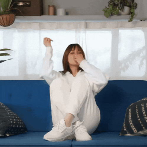 a woman sitting on a blue couch covering her mouth