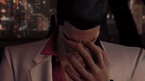a man in a suit is covering his face with his hand