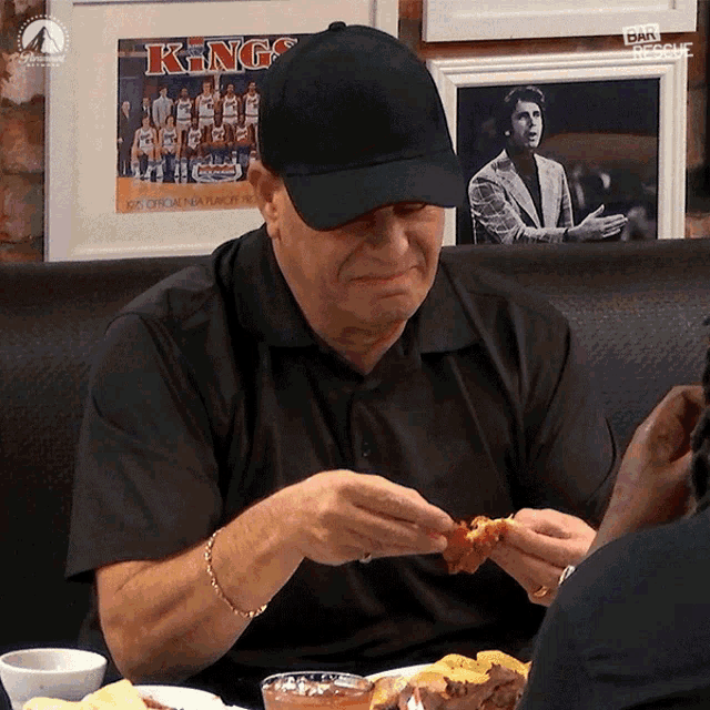 a man wearing a black hat is eating a piece of food