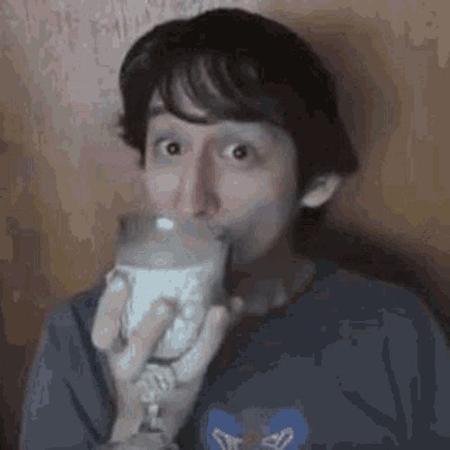 a man is drinking from a wine glass while making a funny face .