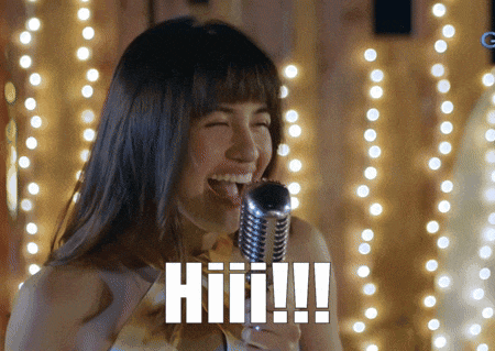 a woman singing into a microphone with the word hiii written on the bottom