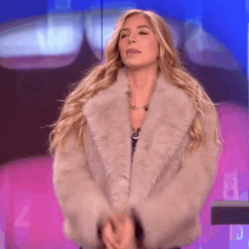 a woman wearing a fur coat is standing in front of a blue wall