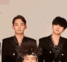 a group of young men in suits are standing next to each other .