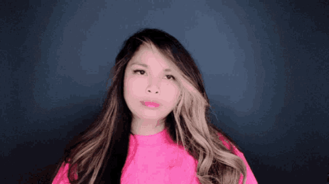 a woman with long hair is wearing a bright pink shirt