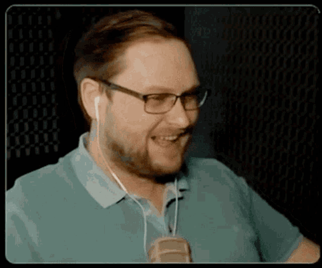 a man wearing glasses and ear buds is smiling and laughing .