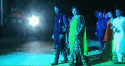 a group of people are standing in a dark room with blue lights behind them