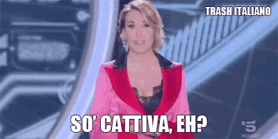 a woman in a pink suit is standing on a stage and says so ' cattiva eh ?