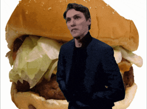 a man in a suit stands in front of a hamburger with lettuce and cheese