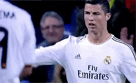 a soccer player wearing a fly emirates jersey is standing in front of another player .