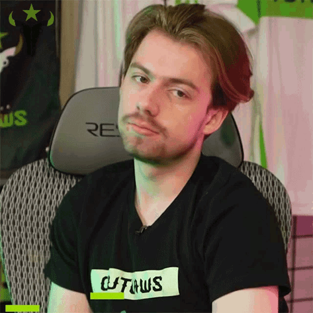 a man wearing a black shirt that says citrus is sitting in a chair