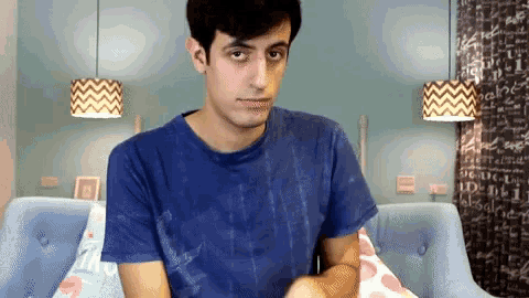 a man in a blue shirt is sitting on a couch with a pillow that says i love you