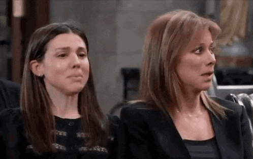 two women are sitting next to each other in a room . one of the women is crying .