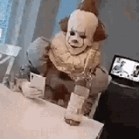 a clown is sitting at a table with a bottle of wine and a cell phone .